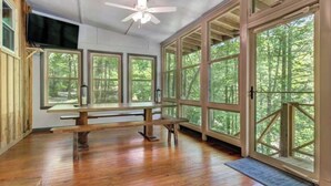 A spacious room with large windows, a ceiling fan, and a wooden bench.