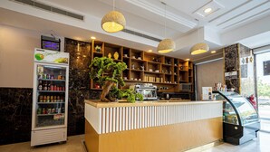 A reception area with a vending machine, a wooden reception desk, shelves with various items, and a potted plant.