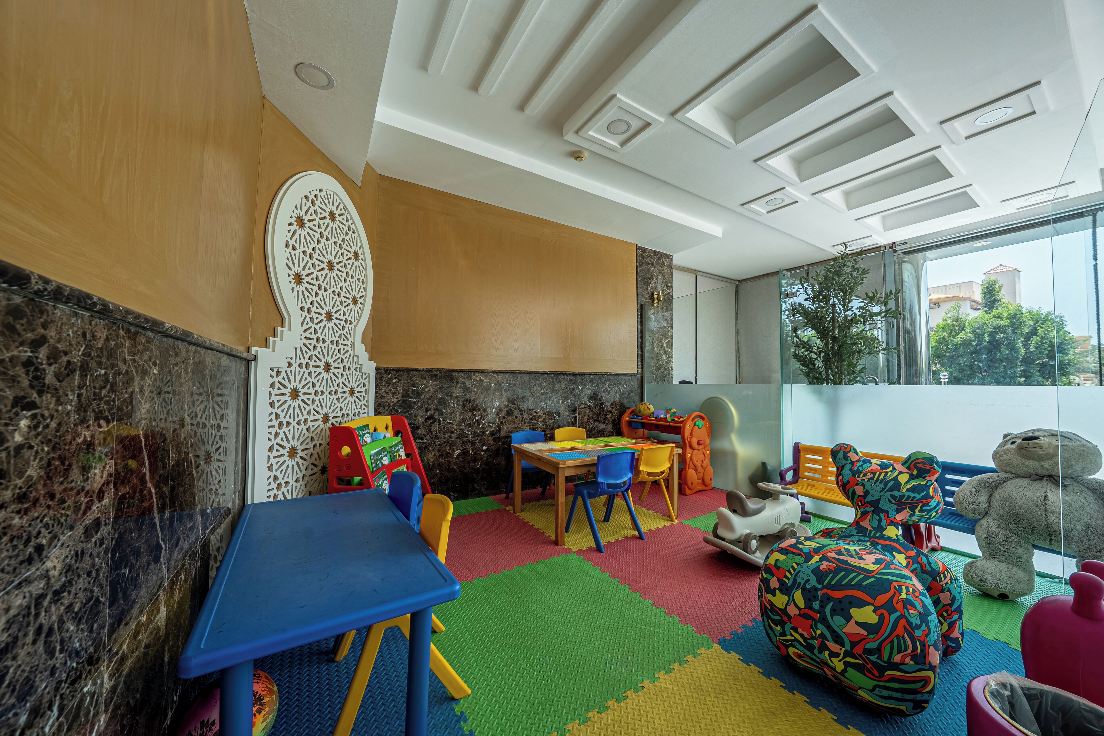 Une salle de jeux pour enfants avec un mur en bois, une grande fenêtre et une vue sur l’extérieur.