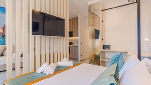 Ein Hotelzimmer mit Bett, Fernseher, Schreibtisch und Blick auf eine Stadtlandschaft.