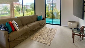 Una sala de estar moderna con un sofá seccional grande, una mesa de centro de vidrio y un televisor de pantalla plana montado en la pared.