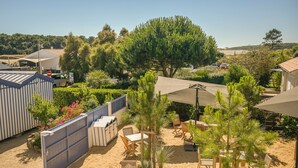 A sandy outdoor area with wooden furniture and a large tree. - Domaine Les Clayères (Talmont-Saint-Hilaire)