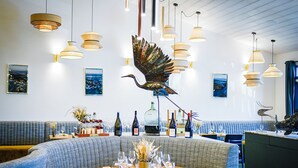 A restaurant with a round table set for dining, a large bird sculpture, and multiple hanging pendant lights. - Domaine Les Clayères (Talmont-Saint-Hilaire)