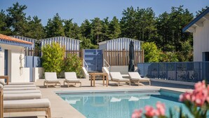 A swimming pool area with lounge chairs and a wooden table. - Domaine Les Clayères (Talmont-Saint-Hilaire)