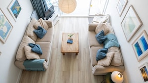 A modern living room with two beige sofas, a wooden coffee table, and a hanging light fixture.