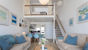 A spacious living area with two sofas, a coffee table, and a staircase leading to an upper level.