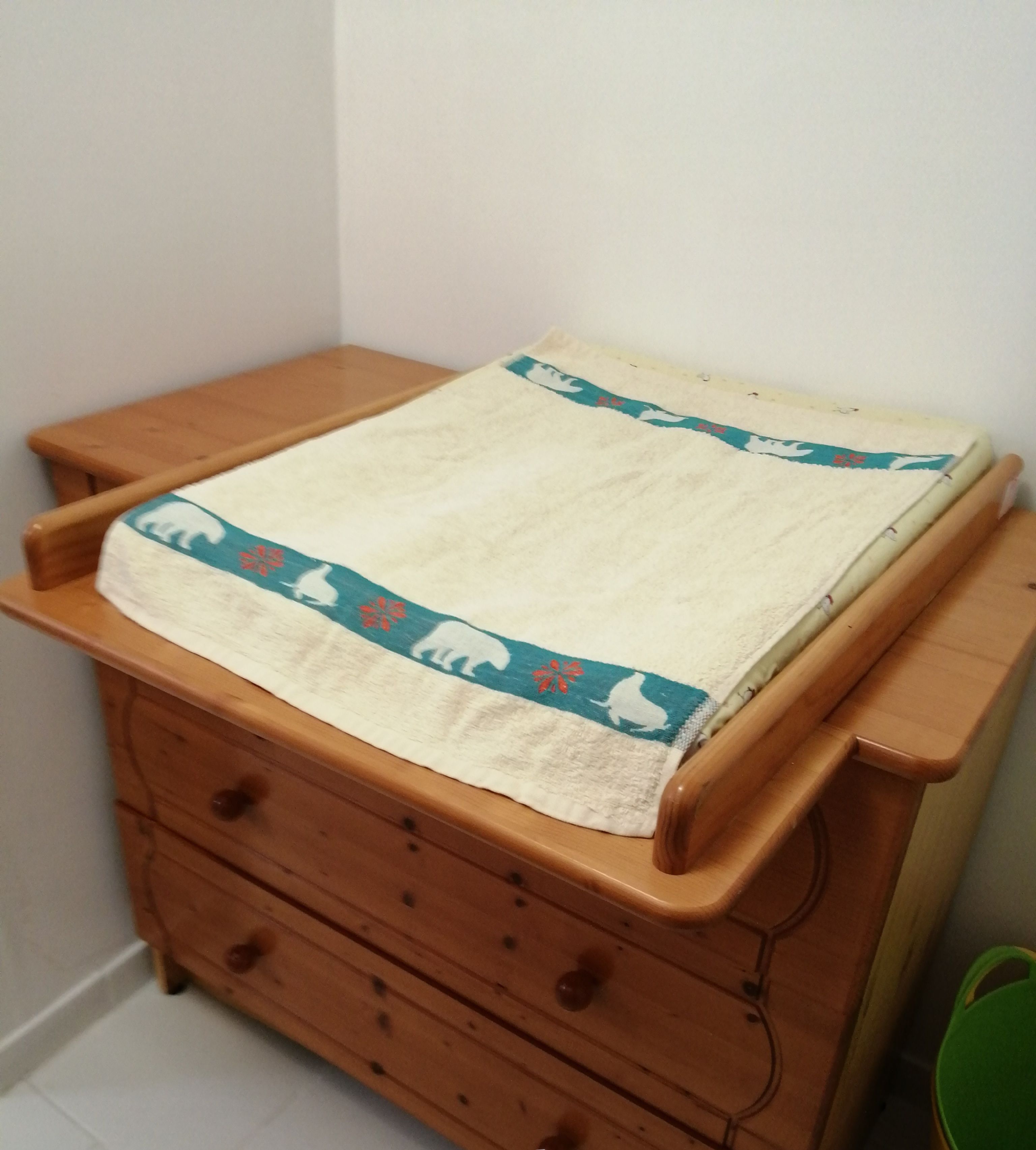 Een houten ladekast met een handdoek erop, in een badkamer.
