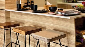 A modern kitchen with wooden cabinetry, a central island with stools, and pendant lighting.