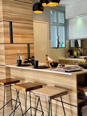 A modern kitchen with wooden cabinetry, a central island with stools, and pendant lighting.