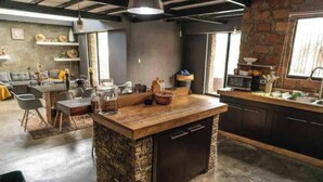 Una cocina moderna con una isla central, armarios oscuros y una pared decorativa de piedra.