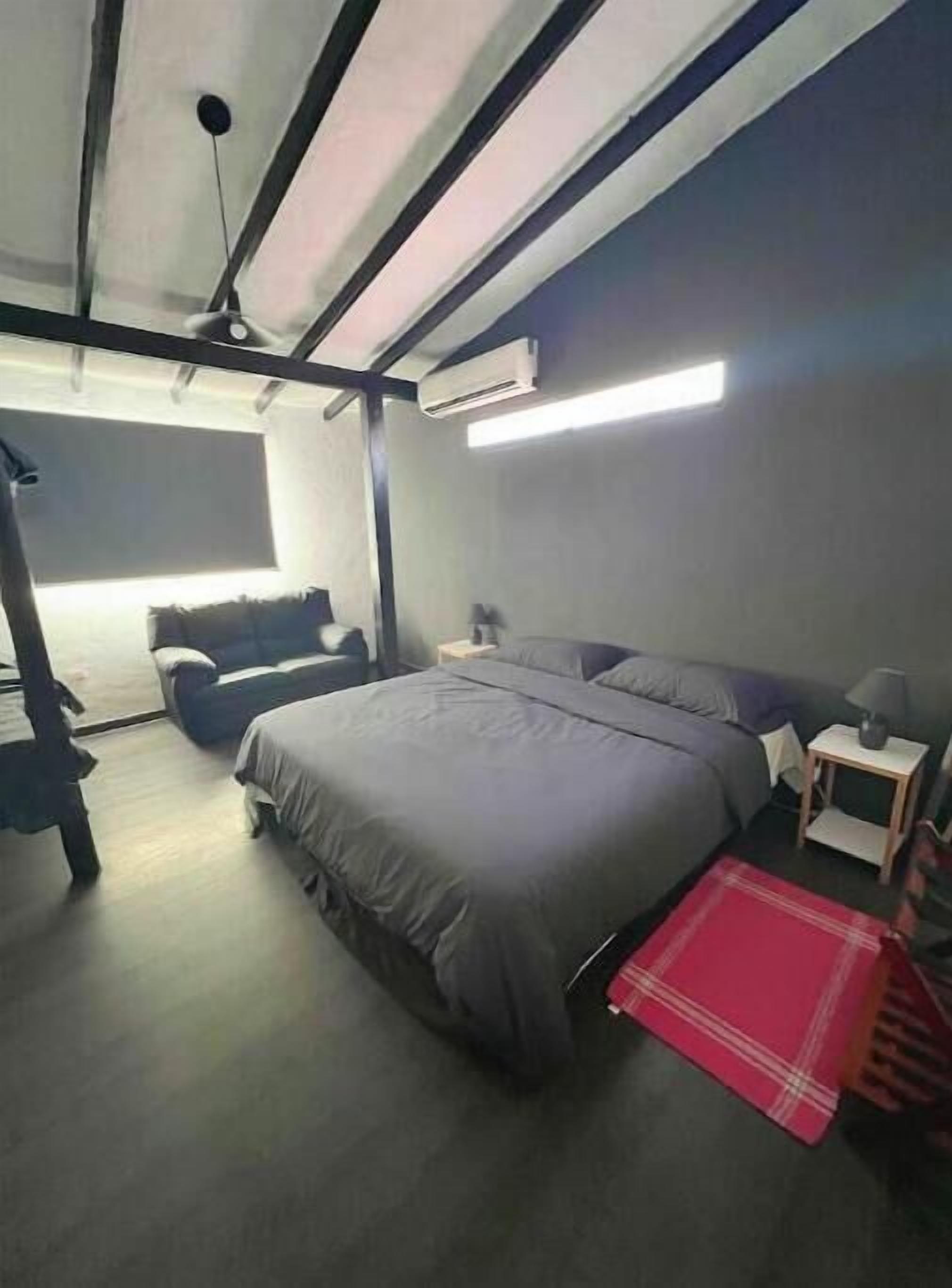A bedroom with a bed, a chair, a nightstand, and a red throw blanket.