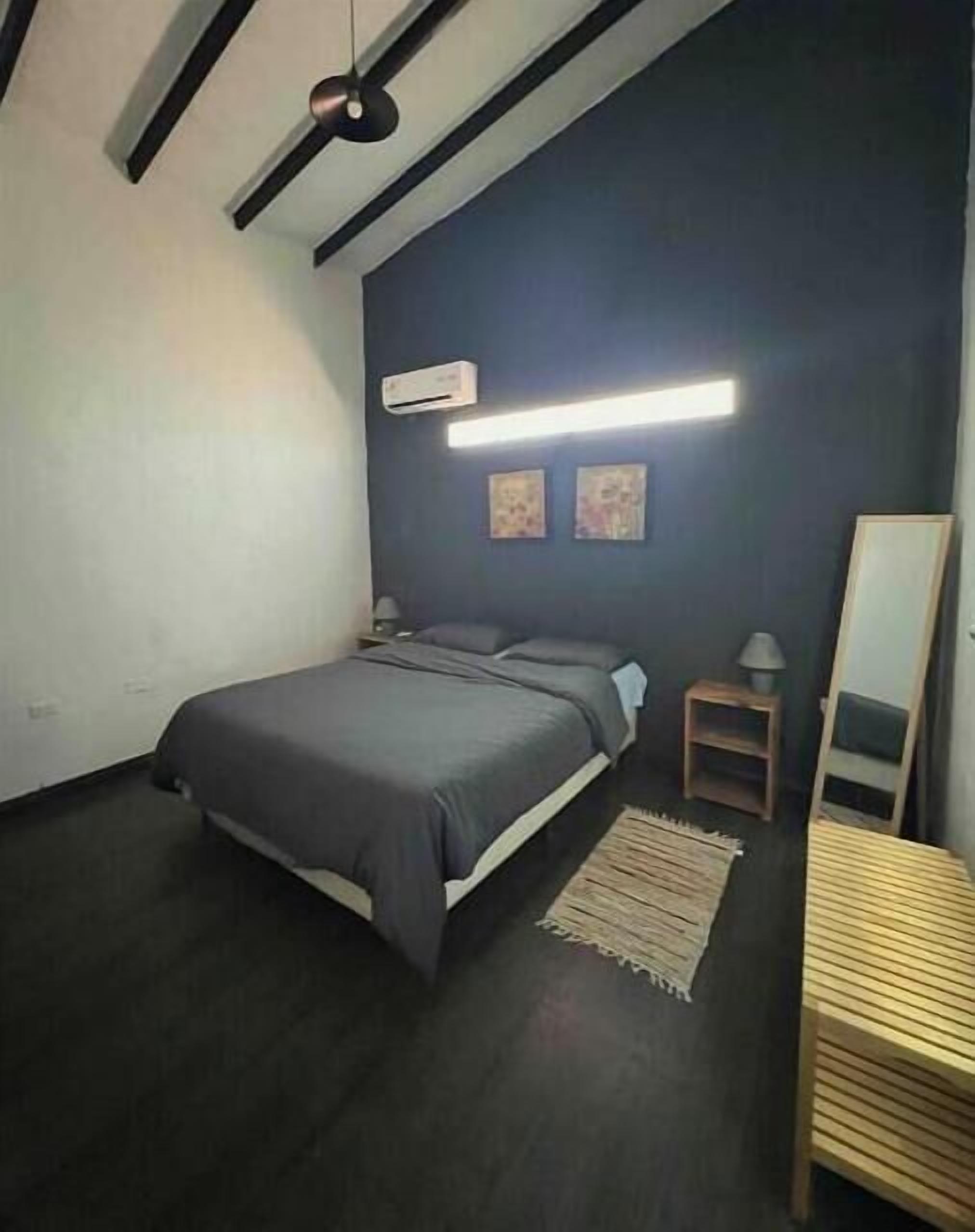 Een slaapkamer met een bed, nachtkastjes, een spiegel en een plafondventilator.