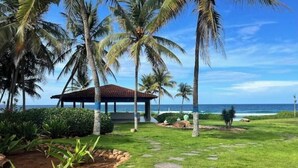 A garden with a gazebo, palm trees, and a view of the ocean.