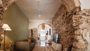 A rustic interior with stone walls, a sofa, a TV, and a lamp. - Colonial House Pool + parking (Mérida)