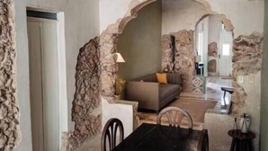 A dining area with a black table and chairs, a bowl of fruit, and stone walls. - Colonial House Pool + parking (Mérida)