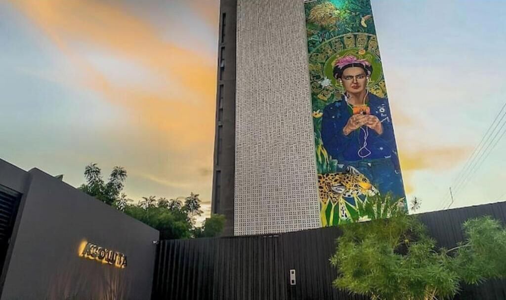 A tall building with a vertical sign featuring a mural of a person holding a phone.