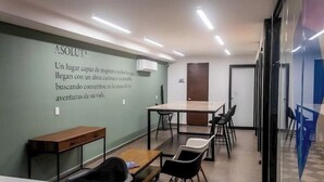 A modern office space with a long table and chairs, a small wooden desk, and a wall with motivational text. - Cozy and elegant loft steps from downtown (Mérida)