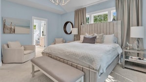 Une chambre à coucher avec un grand lit, un banc, une chaise, une table de chevet et un miroir.