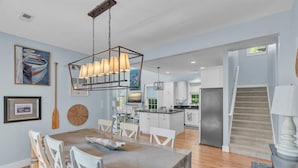 Une cuisine spacieuse avec des meubles blancs, un îlot central et un luminaire suspendu.