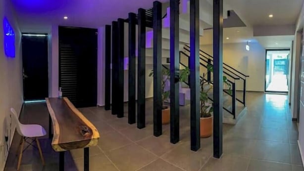A modern interior with a long wooden table and chairs, a staircase, and potted plants. - Comfortable and modern Loft-Exclusive Area Merida (Mérida)