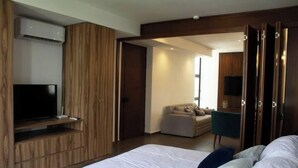 A modern hotel room with a large bed, a TV on a wooden cabinet, a sofa, and a desk. - Comfortable and modern Loft-Exclusive Area Merida (Mérida)