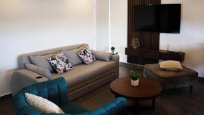 A modern living room with a sofa, two armchairs, a coffee table, and a TV mounted on the wall. - Comfortable and modern Loft-Exclusive Area Merida (Mérida)