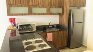 A kitchen with wooden cabinets, a stainless steel refrigerator, a gas stove, and a sink.