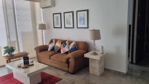 A living room with a brown sofa, a coffee table, a red rug, and a lamp on a side table.