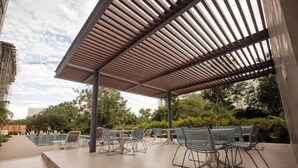 Zona de estar al aire libre con sillas de metal y una piscina al fondo.