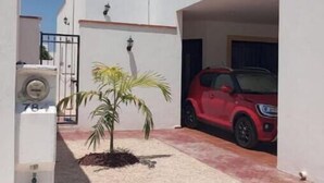 Uma casa moderna de dois andares com um SUV vermelho estacionado na entrada.