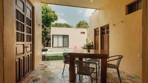 An open patio with a dining table and chairs, a pool in the background, and a patterned floor. - Casa La María: luxury, comfort and private pool (Mérida)
