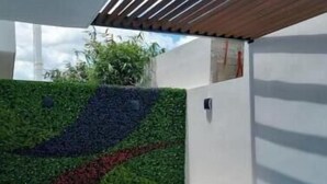 A modern outdoor pool area with a geometric design, a tiered seating area, and a vertical garden wall. - Urban Refuge, Loft with pool and cowork (Mérida)