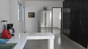 A kitchen with a stainless steel refrigerator, a red blender, and a white countertop.