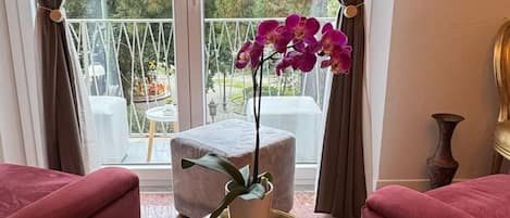A room with two red sofas, a glass table with a gold base, and a window with curtains.