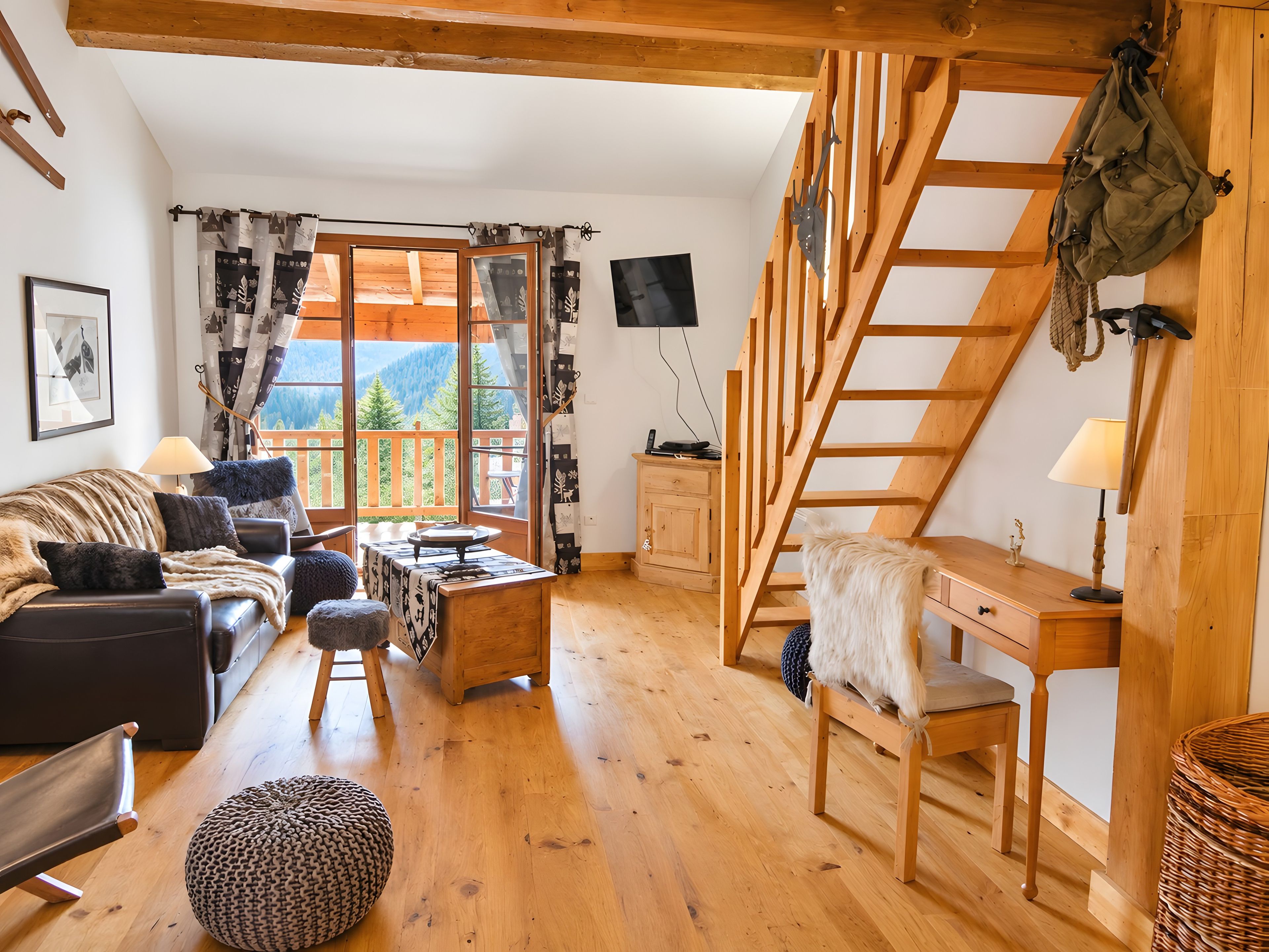 Ein gemütliches Zimmer mit einer Holztreppe, einem Sofa, einem Tisch und Bergblick.