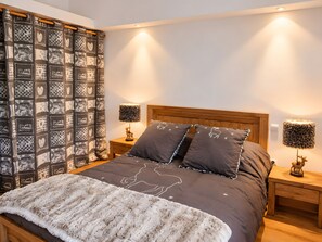 A bed with a patterned headboard, two bedside lamps, and a decorative pillow.
