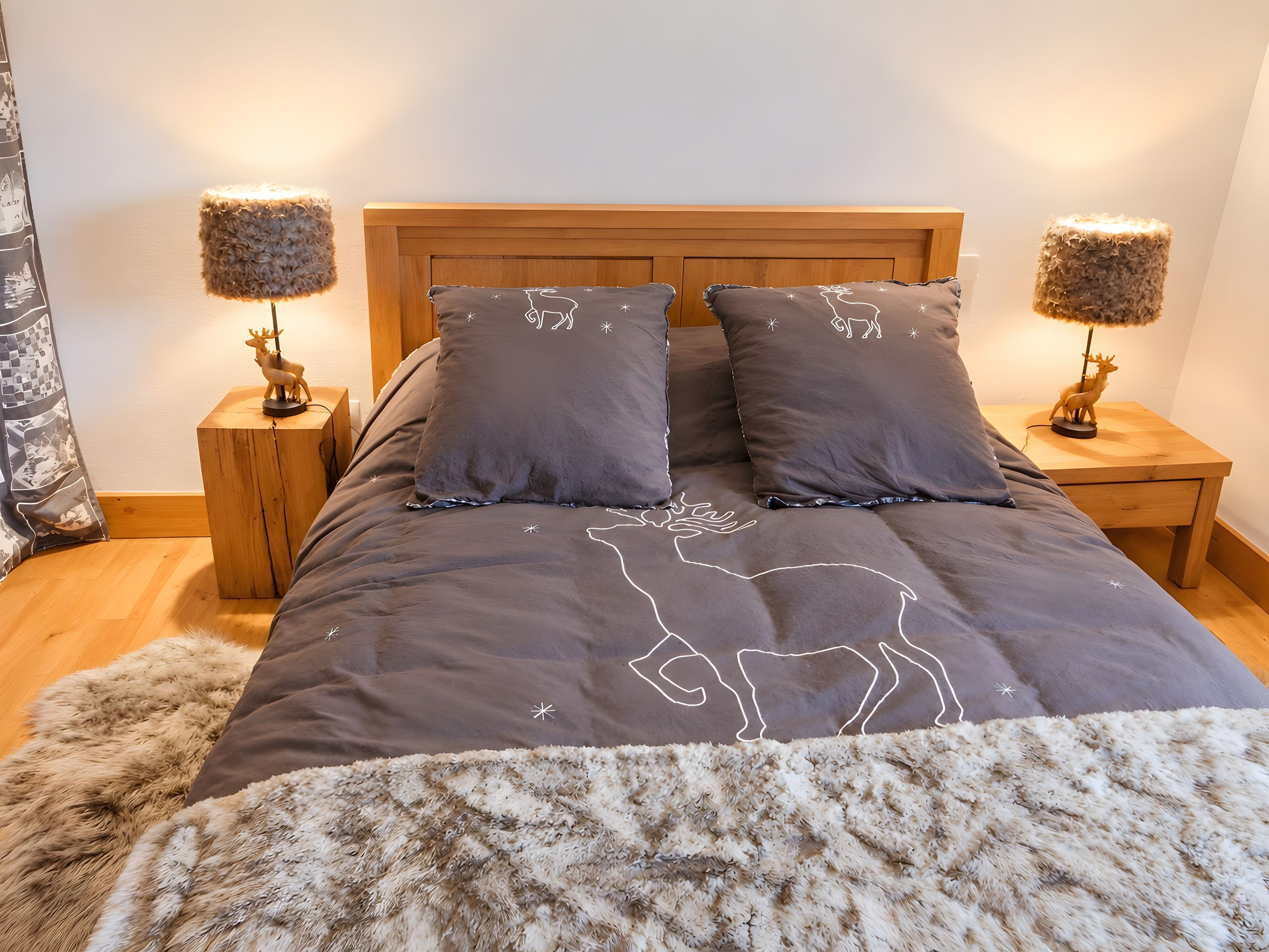 A bedroom with a wooden headboard, two bedside lamps, and a fluffy rug.