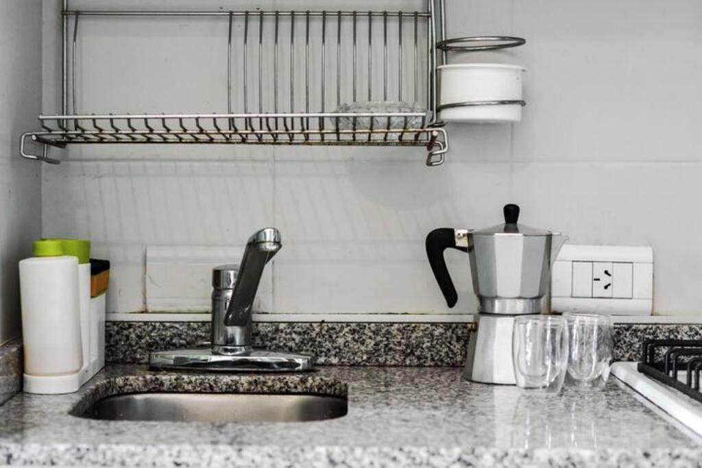 Una cocina con encimera de granito, pileta de acero inoxidable y cafetera.