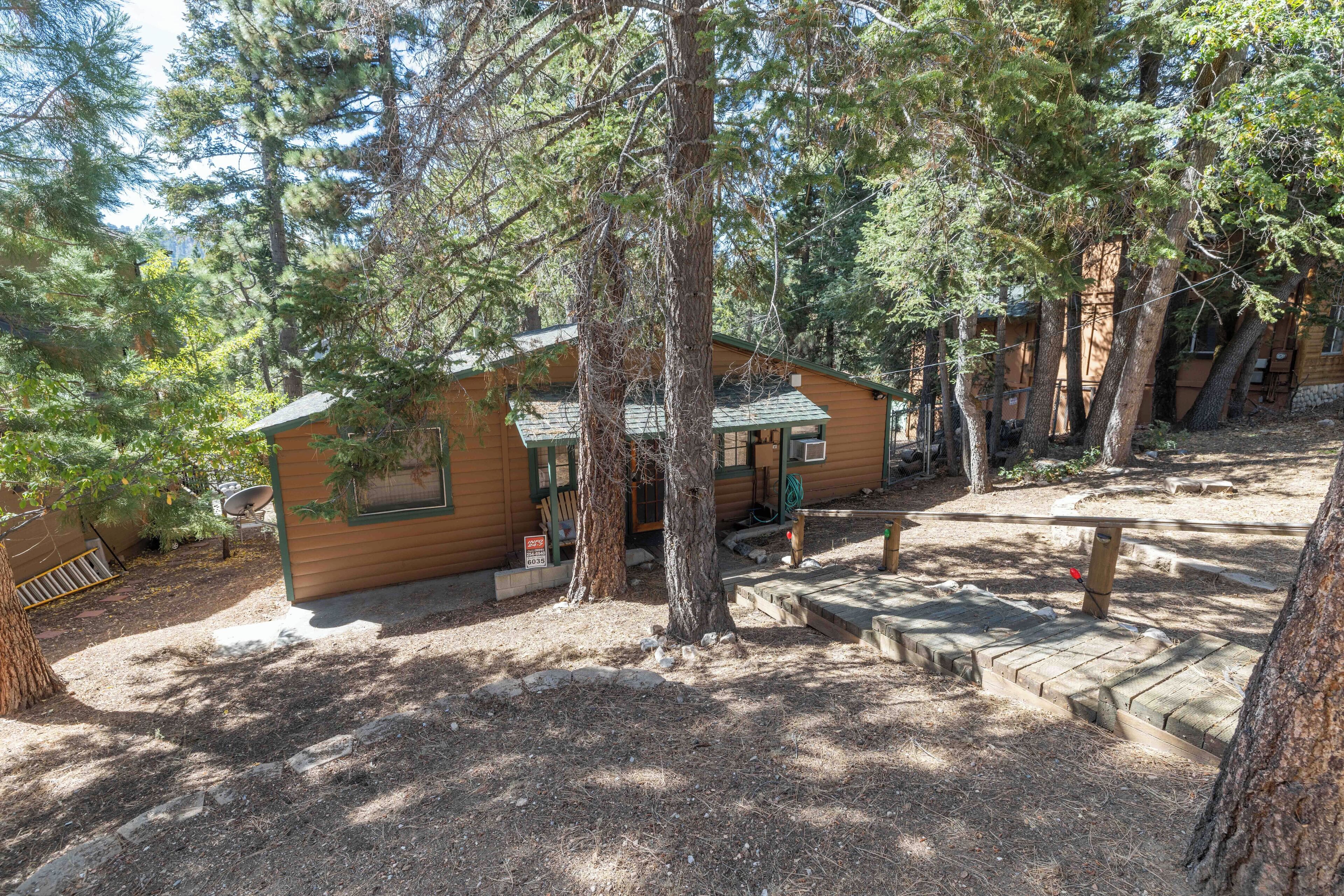 A cabin with a wooden exterior, surrounded by trees, and a small deck area.