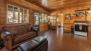 A cozy cabin interior with a wooden interior, a sofa, a dining table, and a kitchen area. - True Big Bear Lake Cabin with jacuzzi (Big Bear Lake)