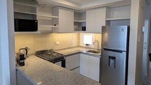 Una cocina compacta con estufa integrada, un lavamanos y un refrigerador.