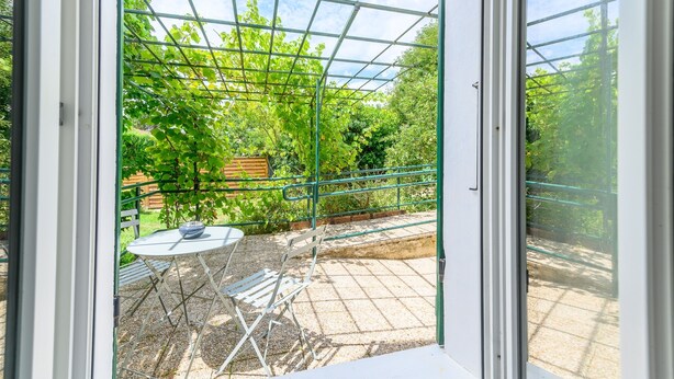 Ein Gewächshaus mit Metallgestell, einem Tisch mit Stühlen und einer Bank.