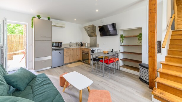 Ett kompakt bostadsutrymme med ett litet k ök, en matplats och en trappa.
