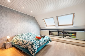 Een slaapkamer met een bed, nachtkastjes, een bureau en een raam.