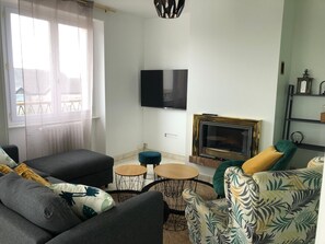 A living room with a sofa, a coffee table, a fireplace, and a TV mounted on the wall.