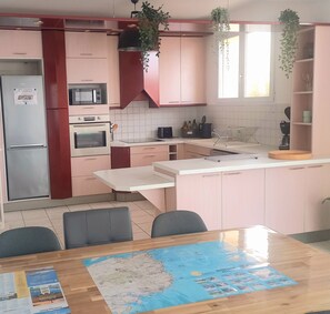 A kitchen with a dining table, chairs, a map, and various appliances.