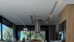 Un salon moderne doté d’un grand canapé en forme de L, d’un coin repas avec une table et des chaises, et d’une cuisine avec des meubles en bois.