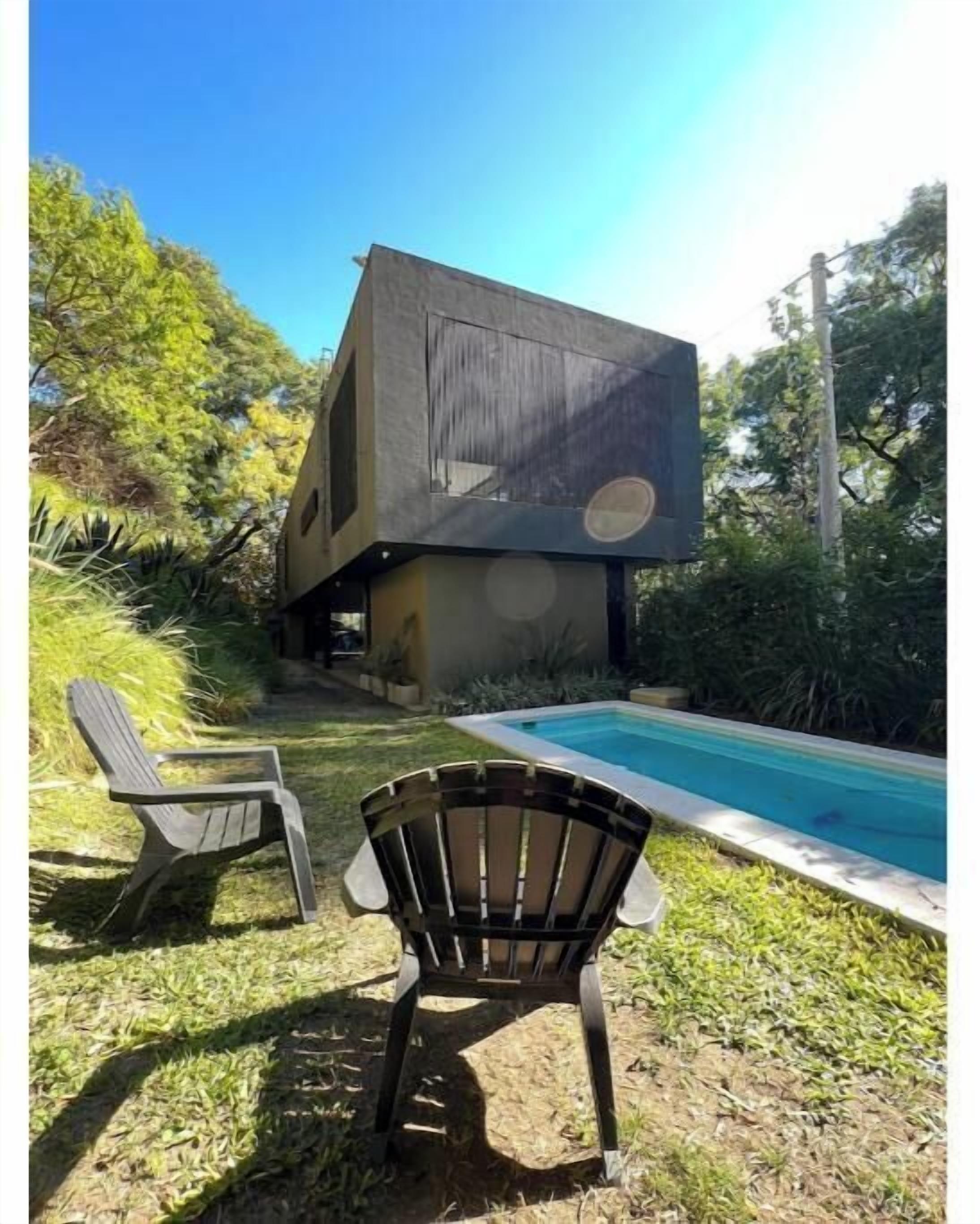 Uma casa moderna com piscina, duas cadeiras e um jardim.