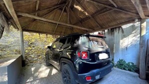 Un SUV noir était garé sous une structure dont le toit était fait de chaume.