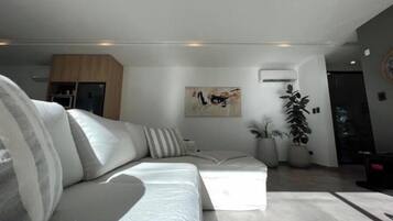 Uma sala de estar moderna com um sofá branco, uma mesa de centro e uma grande planta em vaso.